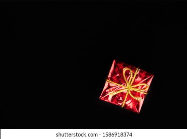 Regalo de Navidad en papel rojo aislado en fondo negro. Caja de regalo.