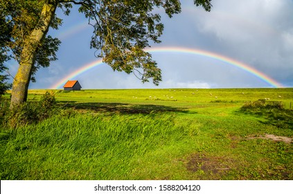 Regenboog in luchtwolken boven landelijk huis gazon zomer veld land landschap