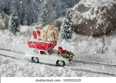 Miniatur mobil klasik membawa hadiah natal di jalan bersalju di lanskap musim dingin yang ajaib