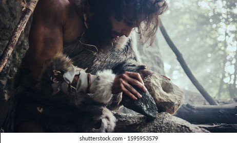 Ein urzeitlicher Höhlenmensch, der ein Tierfell trägt, bearbeitet einen Felsen mit einem scharfen Stein und fertigt ein primitives Werkzeug zur Jagd an. Ein Neandertaler benutzt eine Faustkeil, um das erste Rad herzustellen.