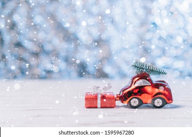 mobil mainan close-up membawa pohon Natal dan kotak dengan hadiah, konsep Natal dan Tahun Baru