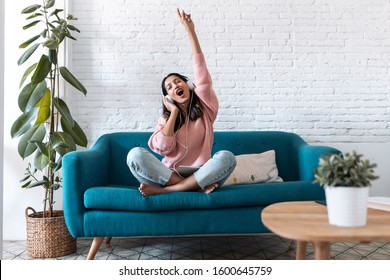 Shot of motivated young woman listening to music with digital tablet while sitting on sofa at home.