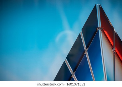 Multicolored detail of glass triangle and metal fixings on a light blue background.