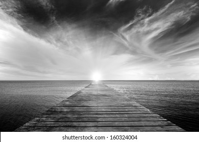 zwart-wit foto van oude brug naar de zee