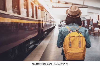 Viajero joven asiática con mochila en el ferrocarril, mochila y sombrero en la estación de tren con un viajero, concepto de viaje. Turista mujer viajero caminando en la estación de tren