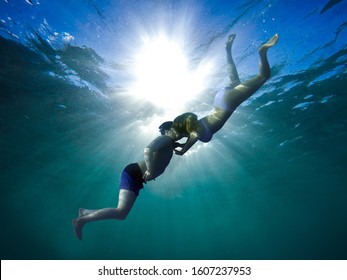 Junger Mann und Mädchen küssen sich unter Wasser - romantische Szene.