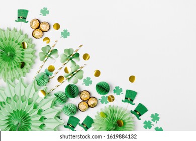 Dekorasi dan properti untuk pesta Hari St.Patrick. Dekorasi kertas hijau dan emas, topi, balon, konfeti, permen dan simbol keberuntungan dengan latar belakang putih. Konsep meriah. Letak datar, tampilan atas.