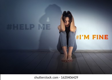 Estrés y problemas psicológicos. Una joven adolescente está sentada en el suelo de una habitación con las manos entrelazadas detrás de la cabeza. Pared de luz en el fondo. La inscripción Ayúdame, estoy bien.