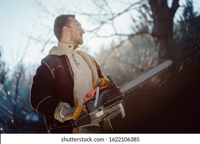 Man with a chainsaw standing in the woods ready to begin work contemplating on the day ahead