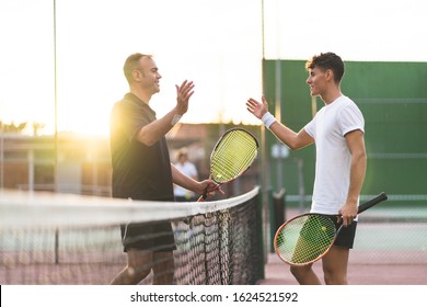 Padre e hijo jugando tenis uno a uno. Familia Haciendo Deporte Juntos. Padre dando un abrazo a su hijo después de jugar al tenis. Concepto de familia.