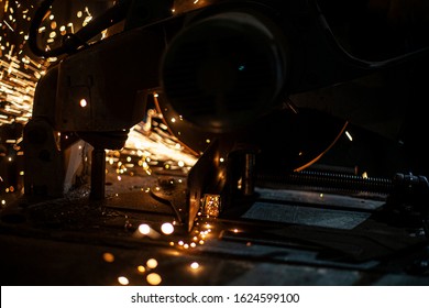 Metal cutting. Grinding steel. Work as a grinder. Sparks from friction. Men's work. Creating a design. The project in the workshop. Iron processing. Hand electric tool.
