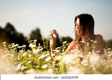 Jovem morena deitada na grama e sorrindo em dia de verão com natureza verde e rio ao fundo. Beleza natural da mulher e conceito de natureza de verão