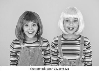Cheerful friends in bright colorful wigs. Anime cosplay party concept. Happy childhood concept. Anime culture influence. Invitation for anime party. Happy little girls smiling faces. Anime fan.