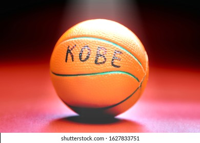 Pelota de baloncesto con inscripción KOBE, fondo rojo. Famoso concepto de jugador de baloncesto. Rayo de luz en la pelota de baloncesto.