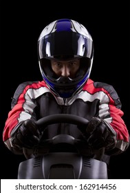 ステアリング ホイールに赤いレーシング スーツと青いヘルメットを身に着けているレーサー