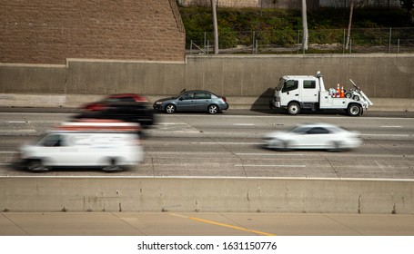 Das Auto, das auf der Schulter der Autobahn mit dem Abschleppwagen gestrandet war, hielt dahinter an und der Verkehr verschwamm, als die Autos an der Szene vorbeirasten