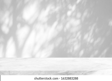 Witte marmeren tafel met boomschaduw op betonnen muurtextuurachtergrond, geschikt voor productpresentatieachtergrond, weergave en mock-up.