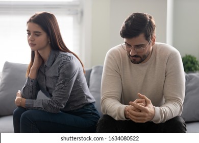 Young couple lost in sad thoughts sitting together on couch thinking feels troubled about problems in relationships, unwanted unexpected pregnancy and difficult decision, break up and divorce concept