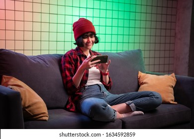 Teenager girl holding a smartphone while playing online shooting gaming.
