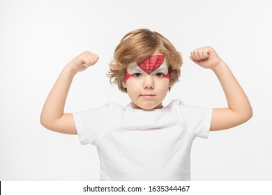 Adorable niño con máscara pintada en la cara demostrando poder aislado en blanco