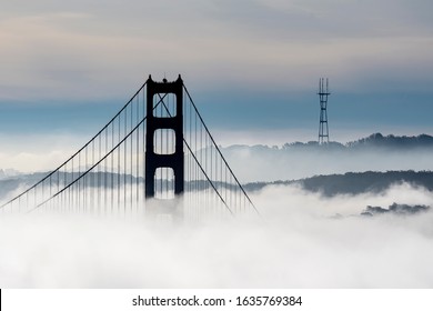 Golden Gate Bridge in silhouette with fog looming all over the tower and landscape