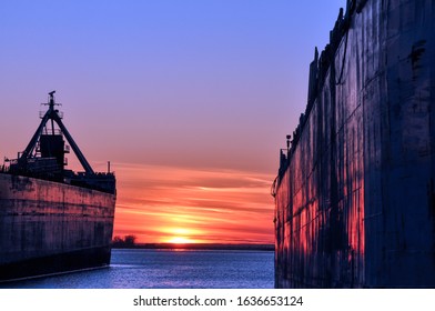 Se ven dos barcos graneleros en el puerto de Toronto, que brillan con un color púrpura anaranjado ardiente al atardecer.