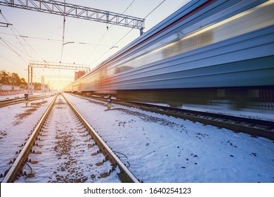 Highspeed train moves fast through the station at winter sunset time.