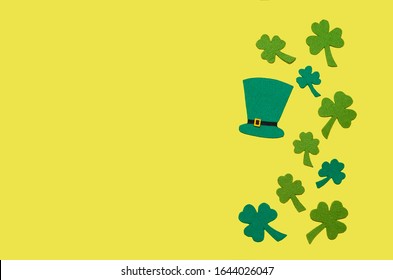 Irlandia merayakan Hari St. Patrick. topi atau topi pria hijau berbaring datar, daun semanggi atau shamrocks dengan latar belakang kuning dengan ruang fotokopi, teks. tradisi Irlandia. fokus lembut