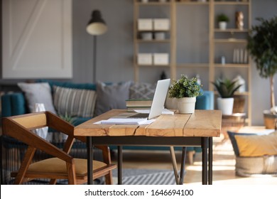 Escritorio de loft de madera vacío con portátil moderno abierto y libro, acogedor diseño interior de salón de estudiante o empleado independiente, cómodo lugar de trabajo doméstico con mesa y ordenador en el apartamento