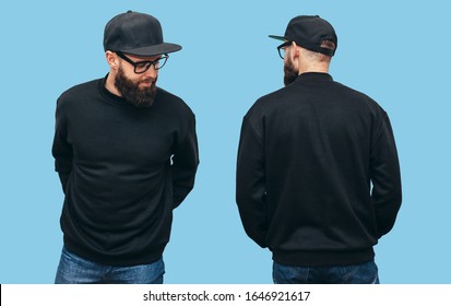ひげを生やしたハンサムな流行に敏感な男で、前面と背面に黒い空白のパーカーまたはスウェットシャツを着ており、青色の背景にロゴやデザイン用のスペースを持つ黒い帽子をかぶっています。印刷用モックアップ
