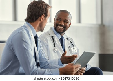 To modne smilende læger diskuterer patientdiagnose og holder digital tablet. Repræsentant lægemiddel diskuterer sag efter positivt resultat med glad læge om ny medicin.