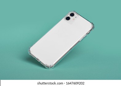 透明なシリコンケースに入った白いiPhone 11が倒れる。緑の背景に分離された背面図モックアップ スマート フォン ケース iPhone 12