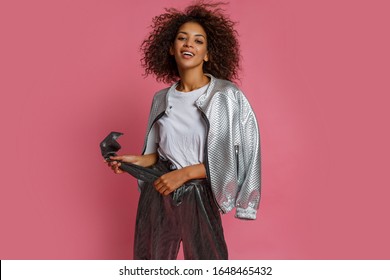 Studio fashion photo of pretty mix race woman with  curly Afro hairs posing on pink background. Spring trendy look.