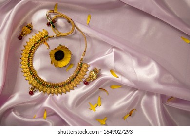 Gold plates silver ginni jewelery on baby pink silk cloth background