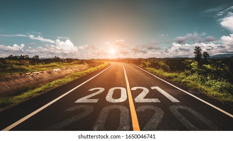 Het woord 2021 geschreven op snelwegweg in het midden van lege asfaltweg bij gouden zonsondergang en mooie blauwe lucht. Concept voor het nieuwe jaar 2021.