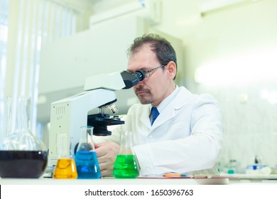 Chemist crazy. A mad scientist conducts experiments in a scientific laboratory. Performs research using a microscope.