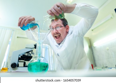 Chemist crazy. A mad scientist conducts experiments in a scientific laboratory. With a mad expression on his face, he mixes two liquids in a flask.