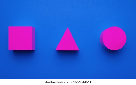 Magenta colored circle, triangle and square made of paper on blue background. Creative futuristic concept. 3d effect.