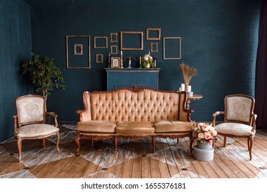 Modern dark interior with a fireplace, flowers, a cozy brown sofa with carved legs and two elegant armchairs. The stylization of the Baroque, classical design, historic interior.