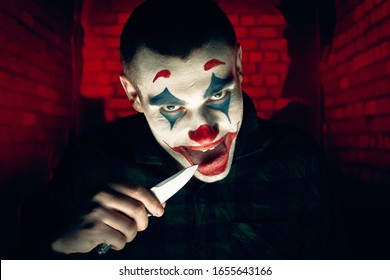 Close-up portrait of a joker man. Stock photo makeup joker in a horror room.