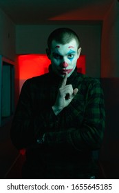 Close-up portrait of a joker man. Stock photo makeup joker in a horror room.