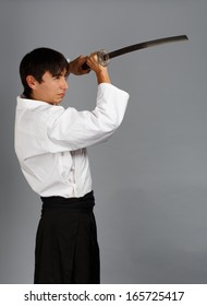 灰色の背景に刀を持って戦うポーズで立っている好戦的な男性