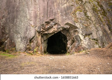 Rotsmuur met een donker gat, ingang aan de grot in Spro, Minerale historische mijn. Nesodden Noorwegen. Nesoddtangen schiereiland.