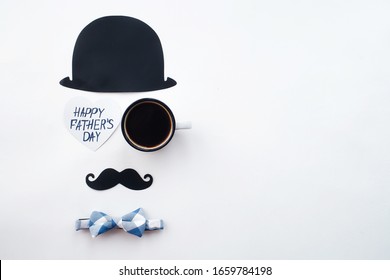 
Holiday concept Father's Day. Flatlay Hat, coffee mug, bow-tie and funny black mustache on a white background. Copy space for text.