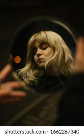 Closeup portrait of a beautiful blonde girl with long curly hair at night with neon lights of the evening city