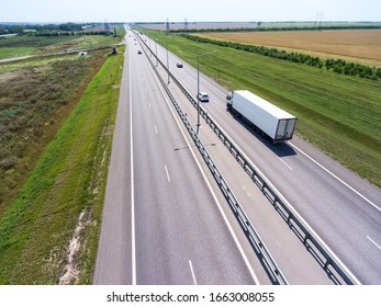 Biała ciężarówka z naczepą jadąca szeroką prostą autostradą na polach uprawnych. Widok z góry. Trasa Don M4 w Rosji