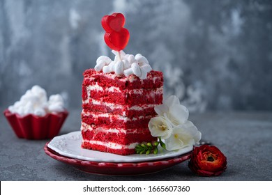 Stück köstlicher roter Samtkuchen mit Zuckerherz und weißem Marshmallow auf Keramikplatten auf grauem Hintergrund. Hochzeits- oder Muttertagskonzept