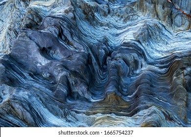 青のバリエーションを持つ岩のディテール。海の浸食効果から生じる曲線と滑らかなカットでいっぱいの岩。岩をクローズアップし、劇的でカラフルな侵食水の形成をテクスチャーします。結石