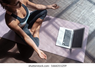 Bovenaanzicht jonge sportieve slanke vrouw coach internet video online training hatha yoga-instructeur moderne laptop scherm mediteren Sukhasana houding ontspannen ademen gemakkelijke stoel pose sportschool gezonde levensstijl concept.