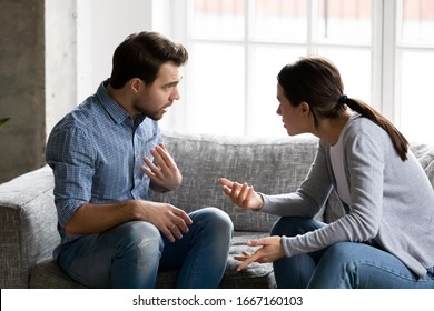 ソファに座って、お互いに講義をしていると非難し、感情的に議論している若い夫婦を強調した。深刻な関係のコミュニケーションの問題を抱えている、妻と喧嘩している落ち込んでいる夫。